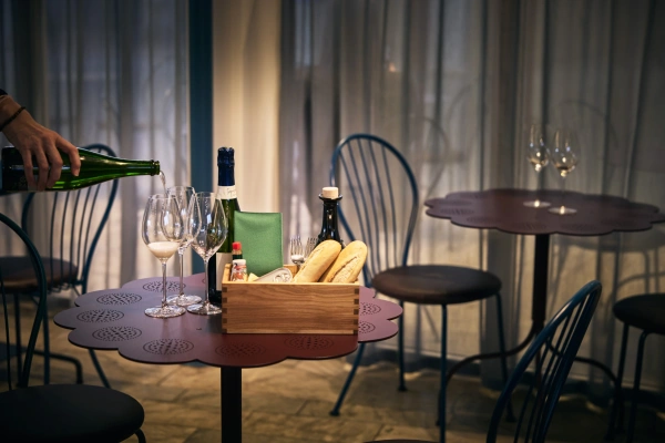 Archipelago, design Jonas Bohlin, mousserande vin hälls upp i ett glas bredvid en box med baugetter och tillbehör